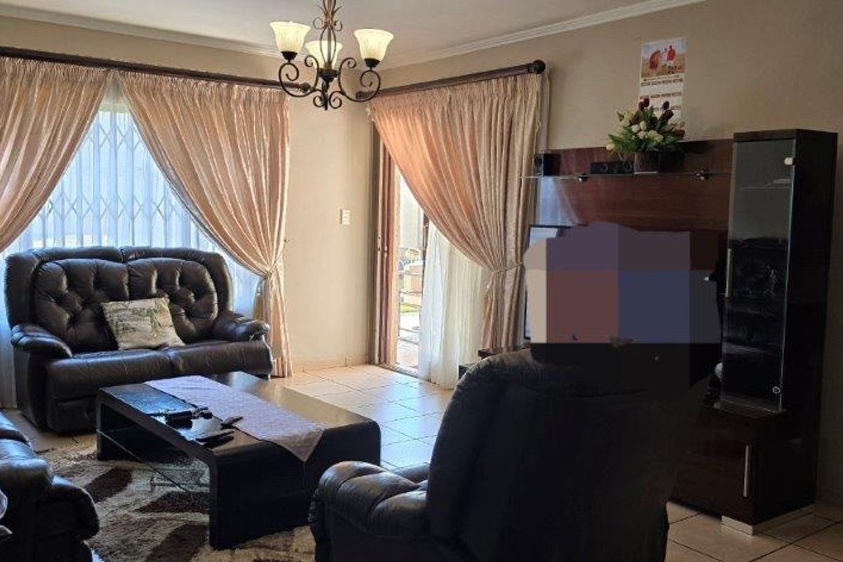 A comfortable living room featuring tiled flooring, cove molding, and a sliding glass door providing access to the outdoor area.