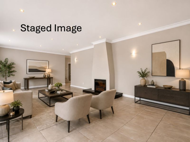 Spacious living room featuring a central fireplace, neutral tiled flooring, and modern recessed lighting with elegant wall sconces.