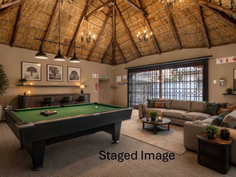 Spacious living area featuring a high thatched roof with exposed timber rafters, a built-in bar, and large sliding doors with security gates.