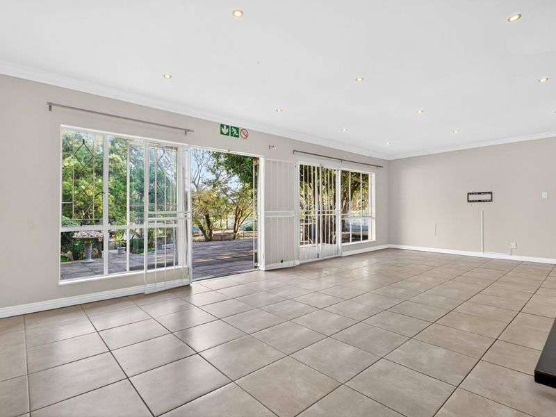 Spacious, light-filled living area featuring neutral tiled flooring, recessed downlighting, and large sliding glass doors providing direct access to the outdoor patio.