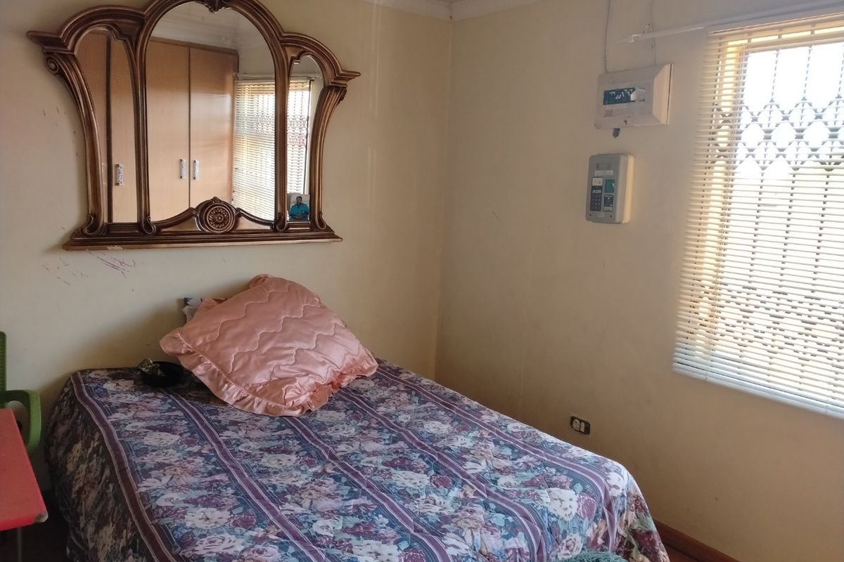 A bedroom featuring built-in cupboards, a security gate on the window, and a wall-mounted prepaid electricity meter.