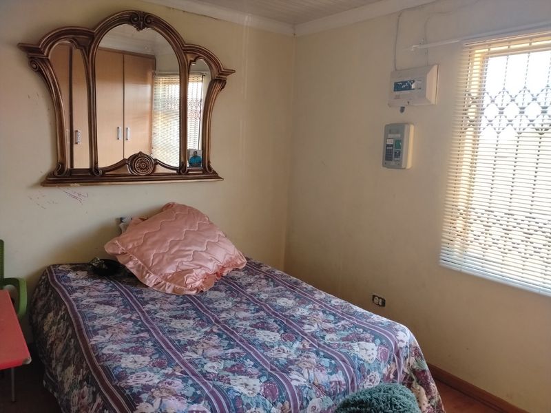 A bedroom featuring built-in cupboards, a security gate on the window, and a wall-mounted prepaid electricity meter.