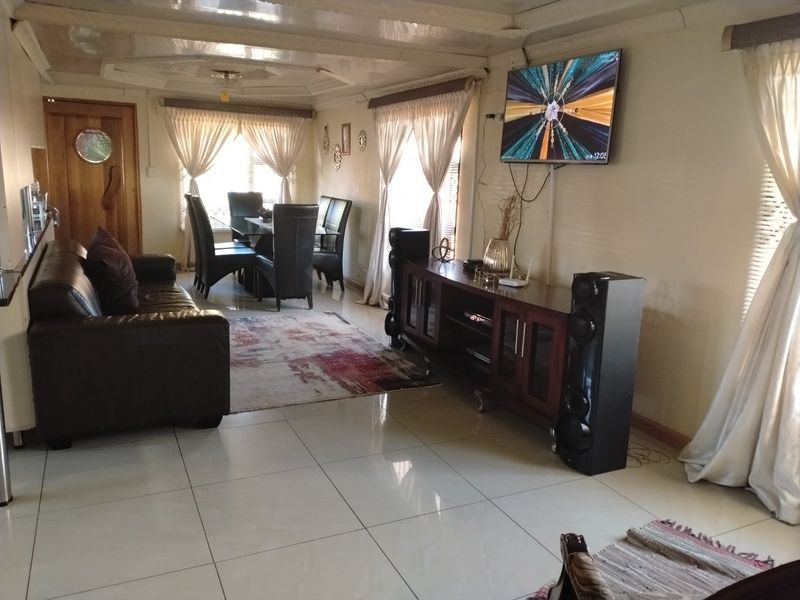 Open-plan living and dining area featuring large format floor tiles and a decorative recessed ceiling.