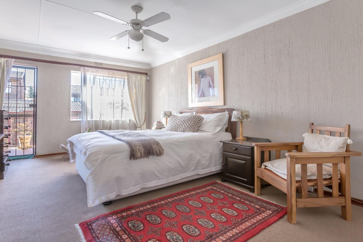 A well-lit bedroom featuring a ceiling fan, textured walls, and a sliding glass door providing access to an outdoor balcony area.