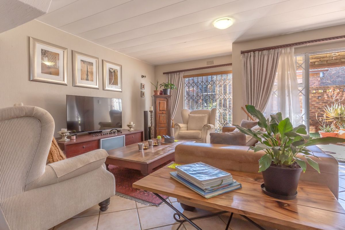 A comfortable living room featuring tiled flooring, ceiling paneling, and a sliding glass door providing access to the outdoor patio area.