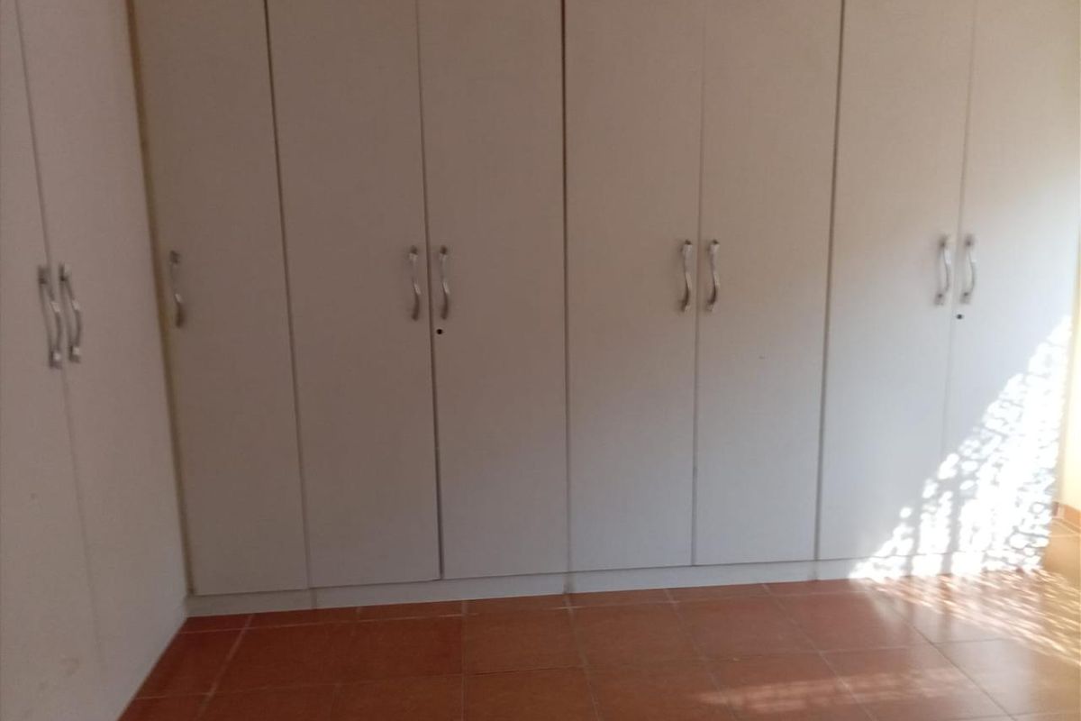 A bedroom featuring built-in cupboards and tiled flooring, presenting a clean and functional space ready for personalization.