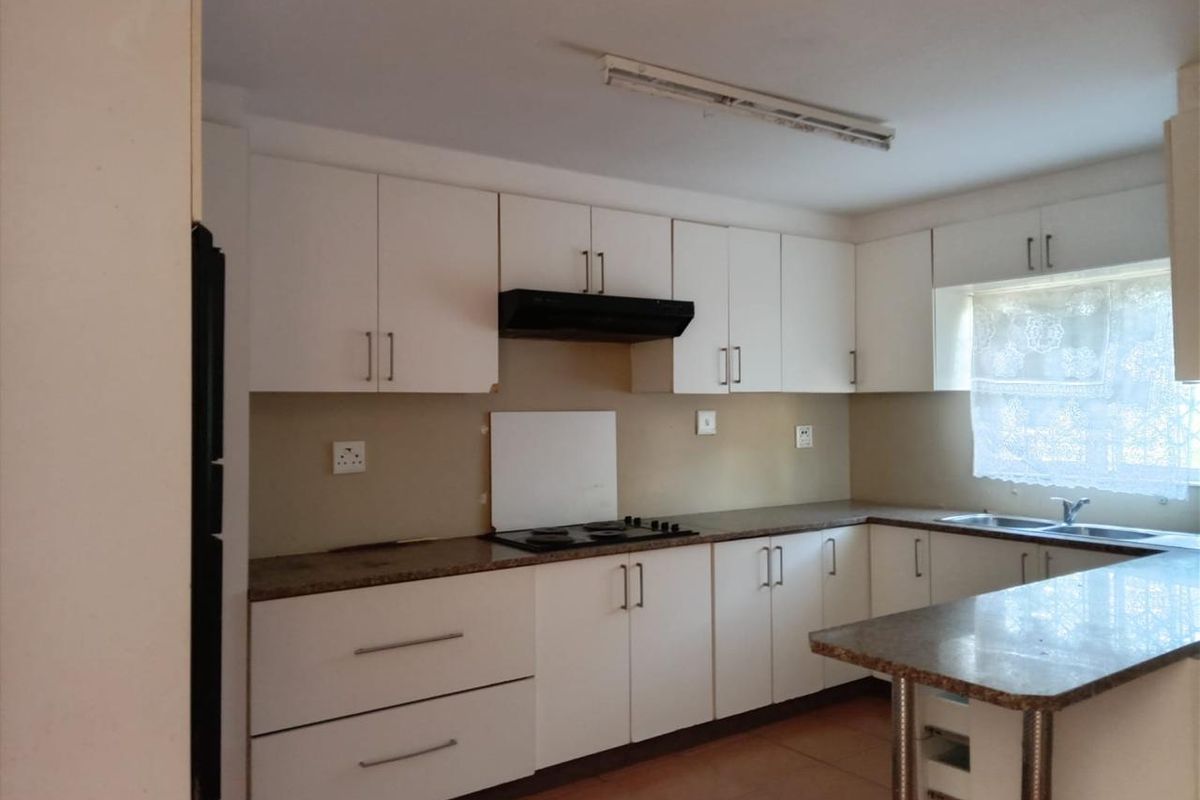 A functional kitchen featuring white built-in cabinetry, granite countertops, a built-in hob with extractor fan, and a double sink.
