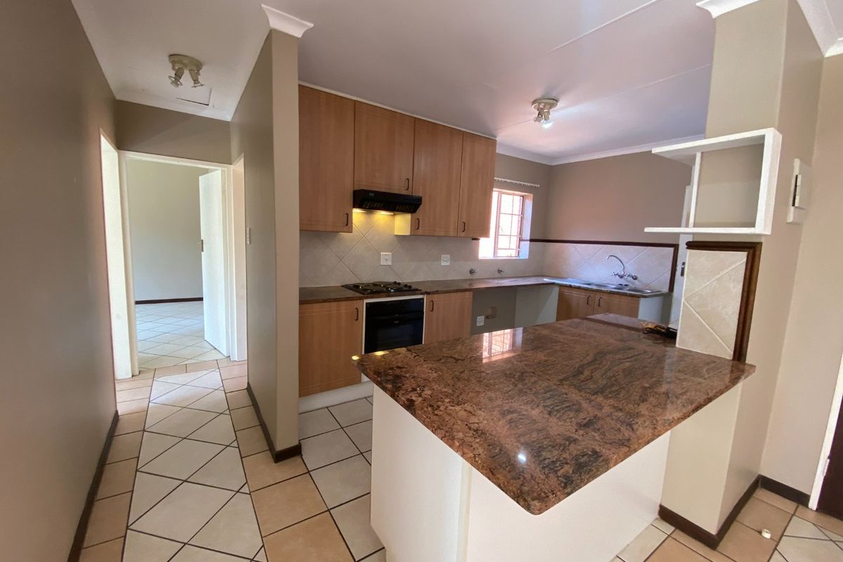 A functional kitchen featuring granite countertops, built-in oven, gas hob, and a breakfast nook, with tiled flooring and neutral cabinetry.