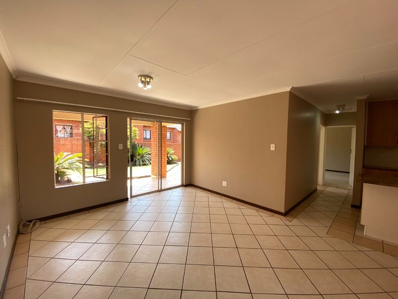 Spacious open-plan living area featuring neutral ceramic floor tiles, sliding glass doors leading to the garden, and direct access to the kitchen.