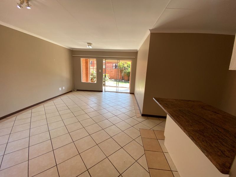 Spacious open-plan living area featuring tiled flooring, a breakfast bar, and sliding glass doors providing direct access to the rear garden.