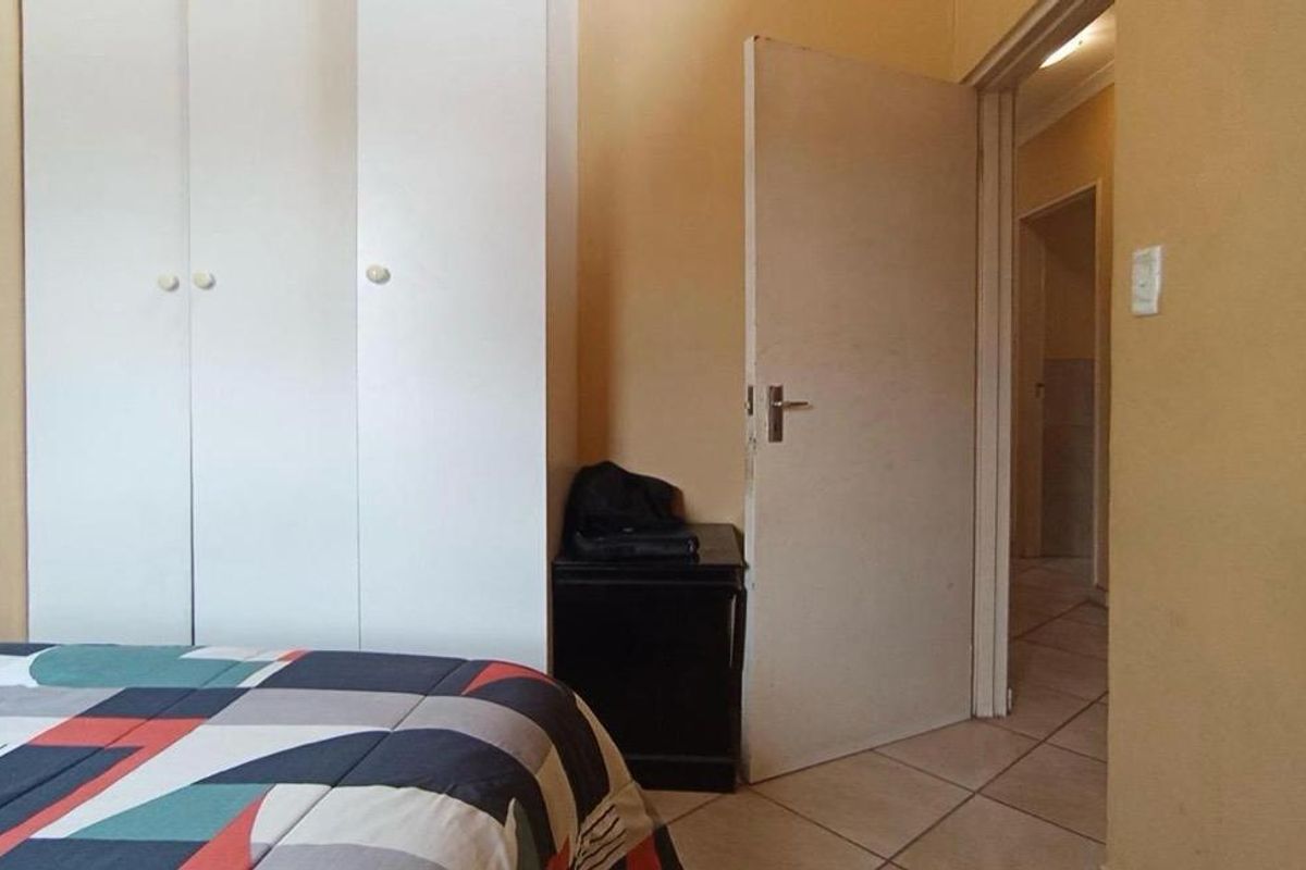 A bedroom featuring built-in cupboards and tiled flooring, providing a functional space with neutral wall finishes.