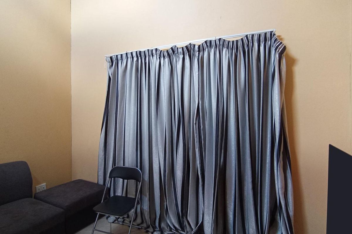 A living room space featuring a wall-mounted curtain track with full-length curtains.