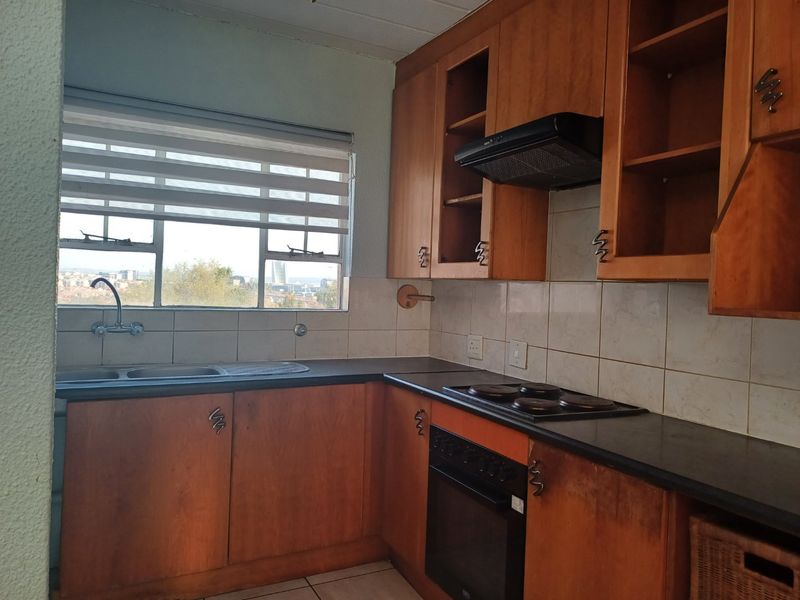 A dated kitchen featuring wooden cabinetry, built-in oven and hob, tiled backsplash, and a window with a view.