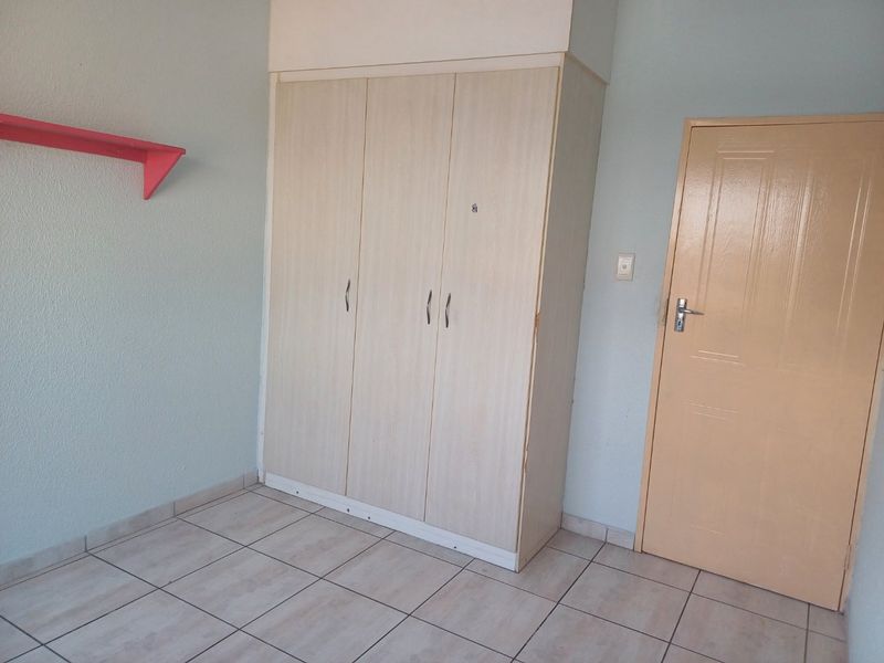 A bedroom featuring tiled flooring and a built-in wardrobe with light wood-grain finish.