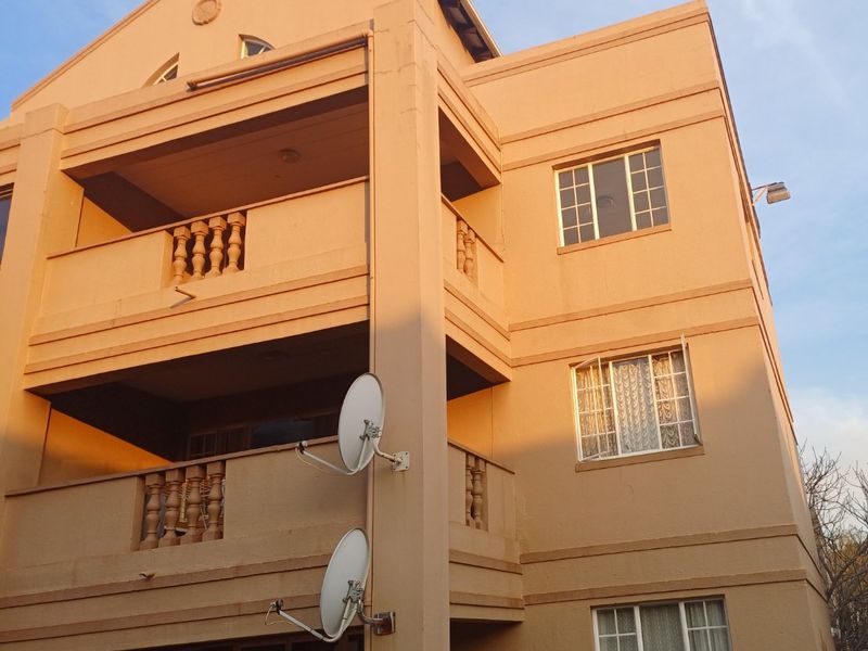 Exterior view of a multi-story apartment building featuring private balconies with balustrades and multiple satellite dish installations.