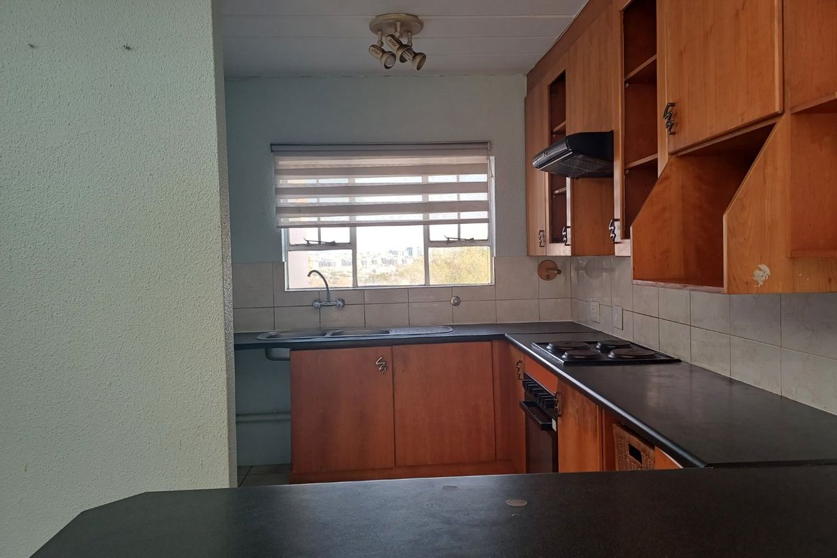 A functional kitchen featuring built-in wooden cabinetry, laminate countertops, a double sink, and integrated cooking appliances with a tiled backsplash.