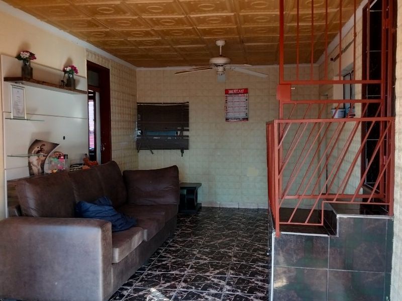 Living area featuring decorative ceiling tiles, a ceiling fan, and tiled flooring with an integrated metal security gate and built-in shelving.