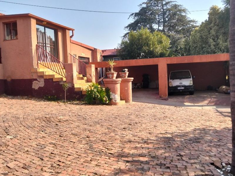 Front exterior view of the property featuring a brick driveway, a covered carport, and an elevated entrance with a staircase.