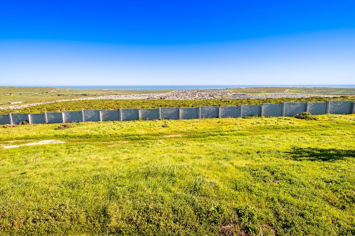A wide-angle view of the vacant residential land featuring a perimeter wall and distant coastal landscape.