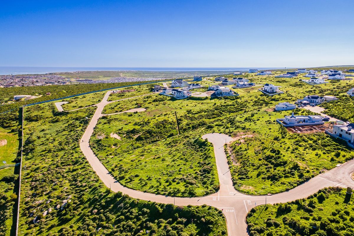 An aerial view of a residential estate development featuring paved roads and surrounding coastal landscape.