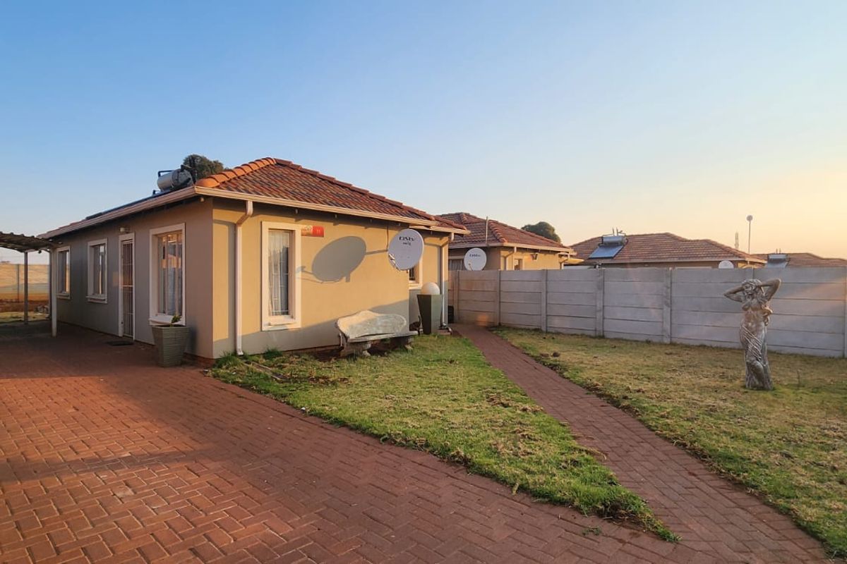 Rear view of the property featuring a paved driveway, carport, and a private garden enclosed by a precast concrete boundary wall.