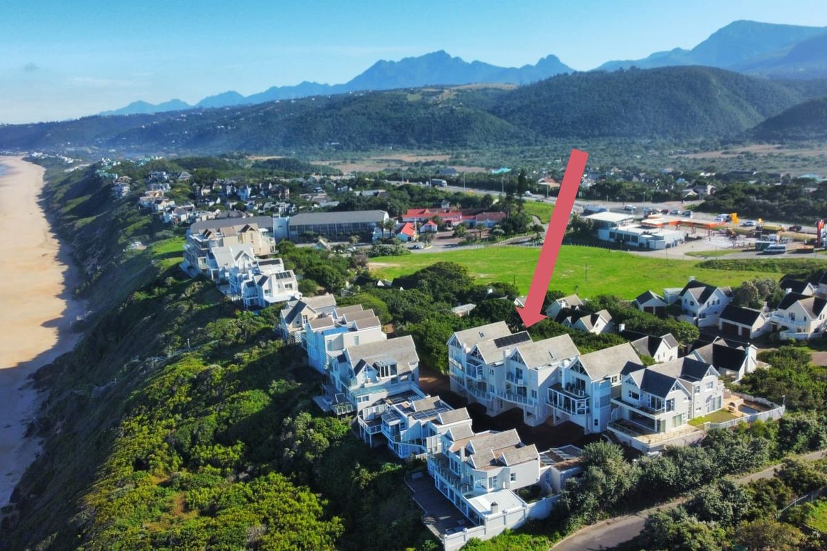 Aerial view of a coastal townhouse development situated on a cliffside, showcasing the property's prime location and proximity to the beach and surrounding landscape.