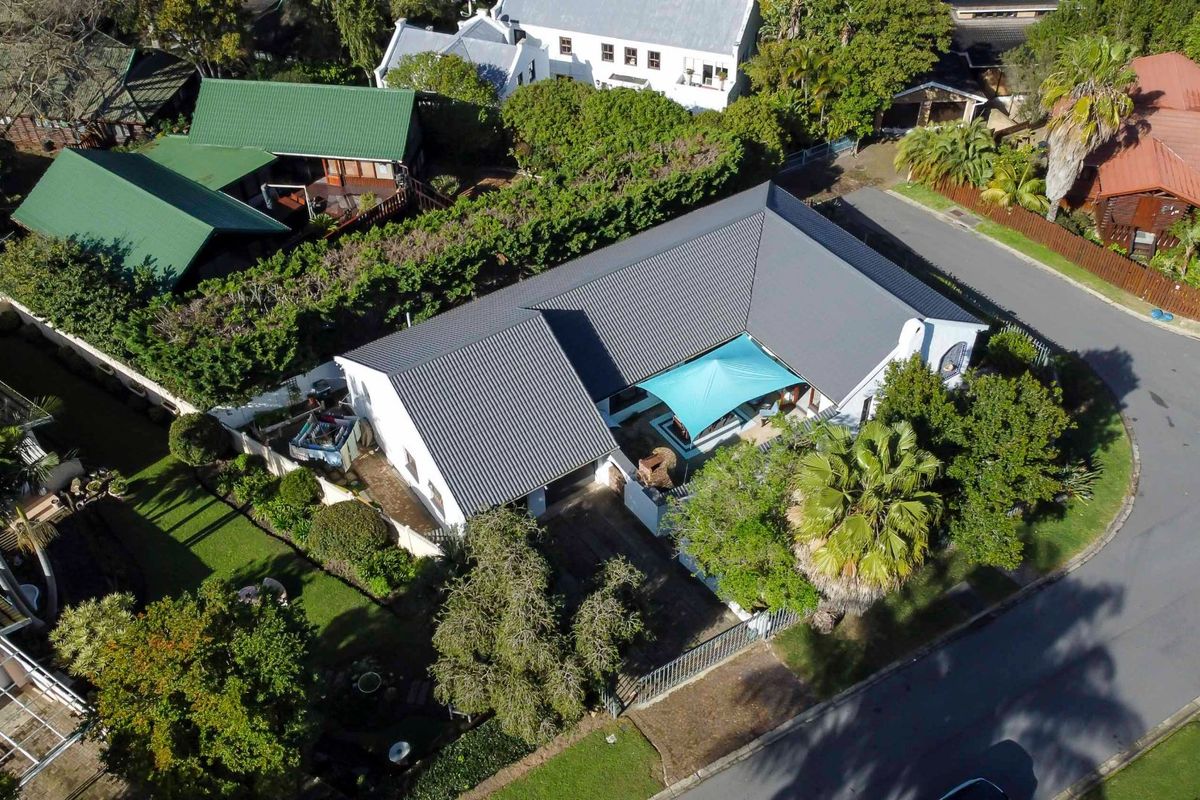 Aerial view of the property showcasing the roof structure, driveway, and surrounding garden area within a residential neighborhood.
