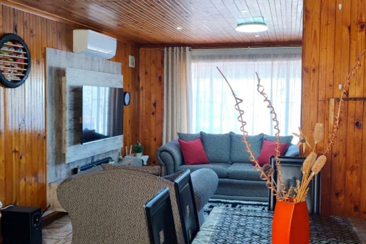 A cozy living room featuring extensive timber wall and ceiling paneling, equipped with a split-system air conditioner and recessed lighting.