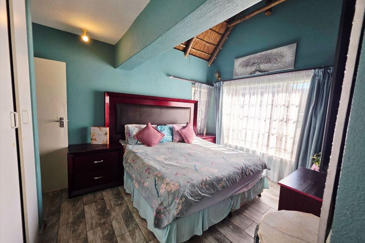 A bedroom featuring a unique thatched ceiling with exposed timber rafters, tiled flooring, and a built-in cupboard.