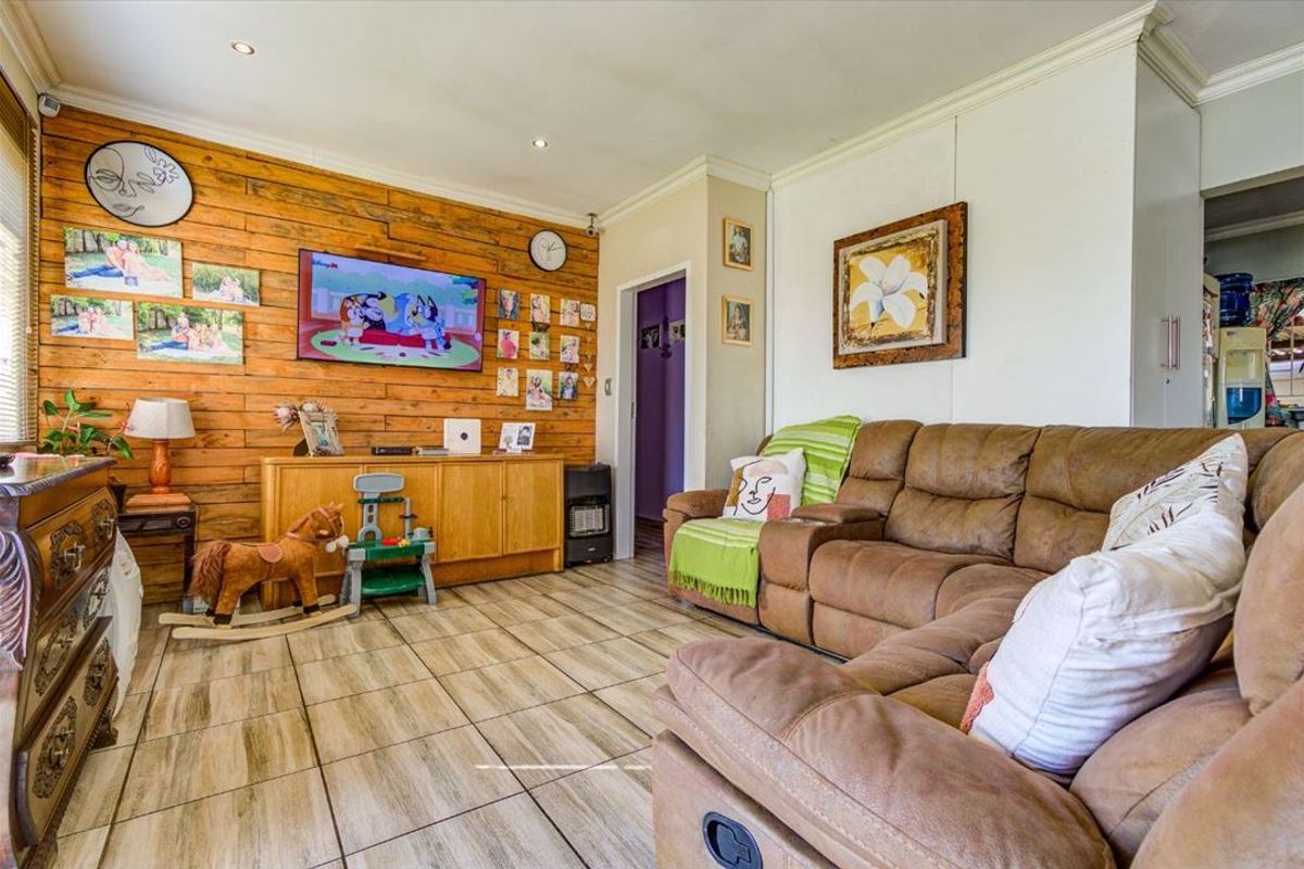 A living room featuring tiled flooring, recessed downlighting, and a decorative timber-clad feature wall.