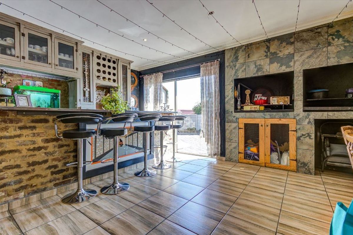 A dedicated indoor bar area featuring a built-in counter, wine storage, and a stone-clad indoor braai, with direct access to the outdoor patio.