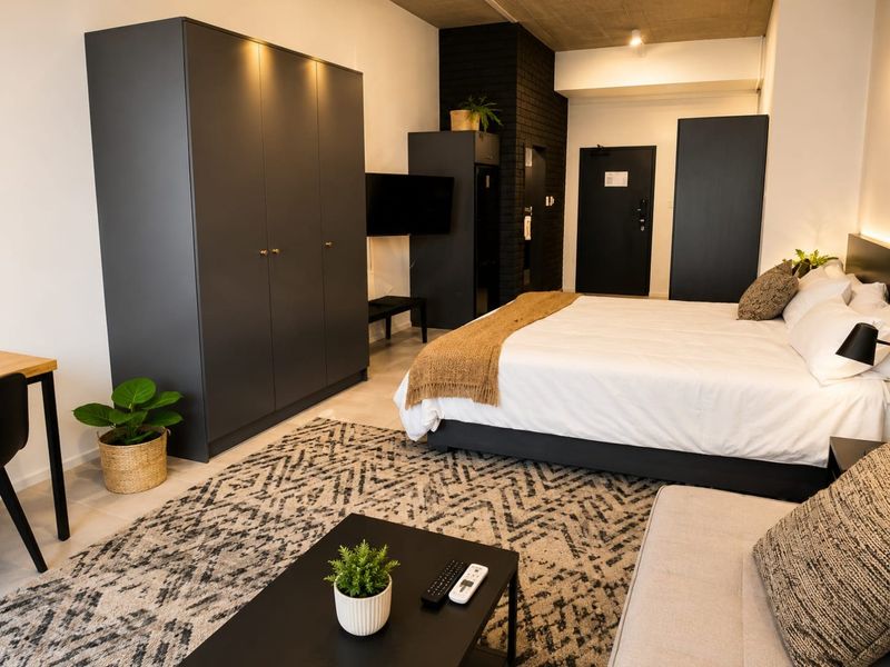 A modern bedroom featuring an exposed concrete ceiling, a dark brick accent wall, and built-in cabinetry, offering a contemporary and stylish living space.