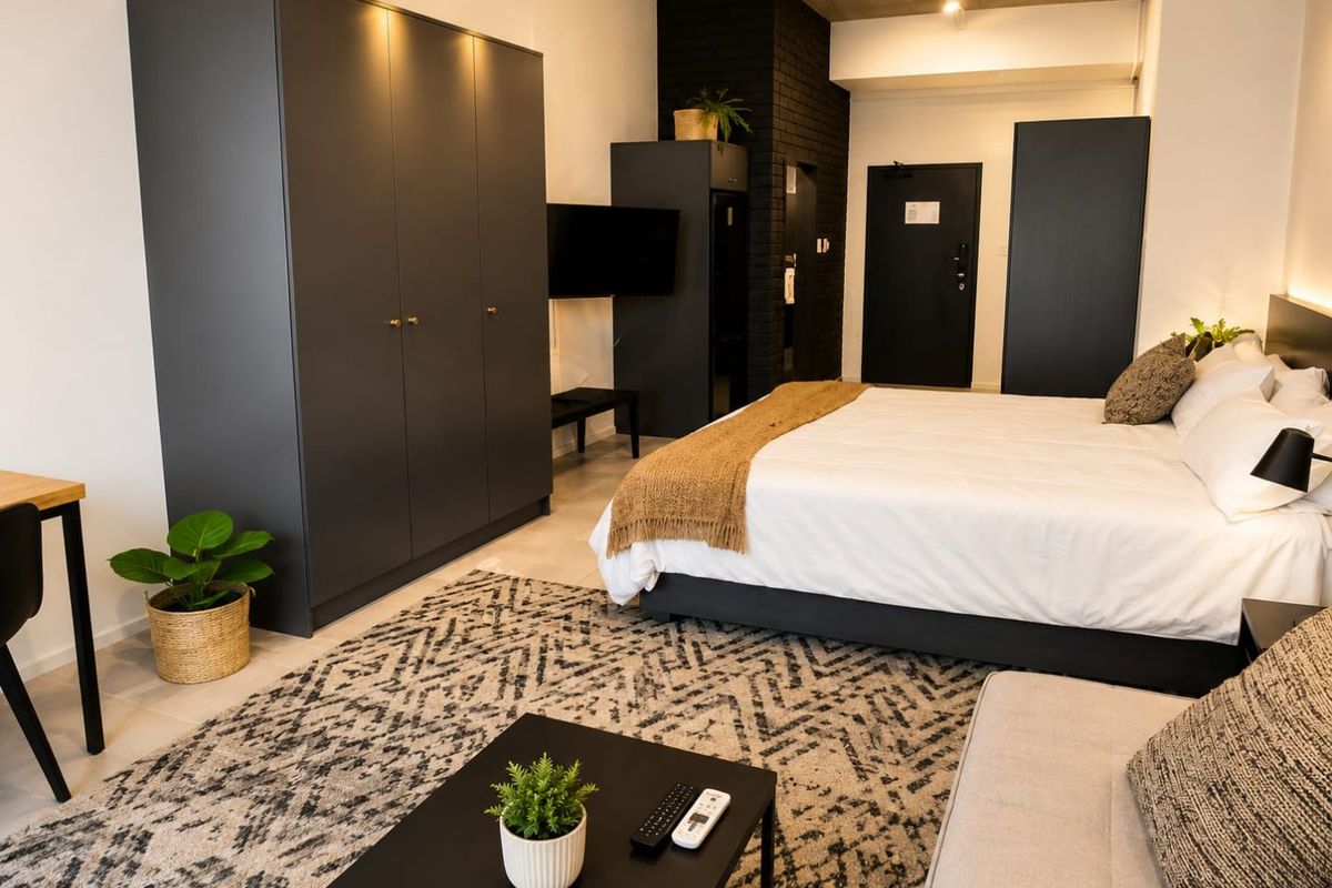 A modern bedroom featuring an exposed concrete ceiling, a dark brick accent wall, and built-in cabinetry, offering a contemporary and stylish living space.
