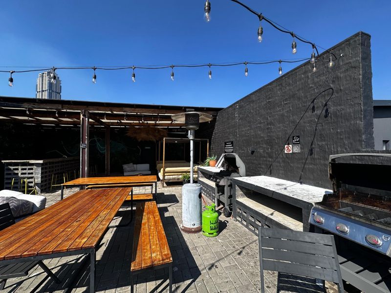 Spacious outdoor patio area featuring a built-in braai, concrete prep surfaces, and a covered pergola, ideal for alfresco dining and entertaining.