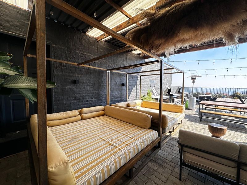 A spacious outdoor patio area featuring paved flooring, a covered roof structure, and perimeter railings, ideal for entertainment and relaxation.
