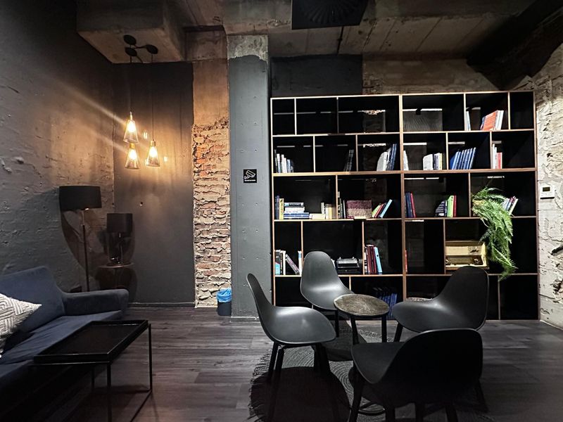 A modern industrial-style living area featuring exposed brick walls, concrete ceiling details, and a large built-in shelving unit.