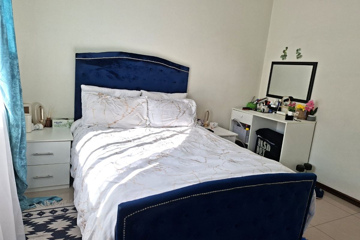 A well-lit bedroom featuring neutral wall finishes and tiled flooring, providing a comfortable and functional sleeping space.
