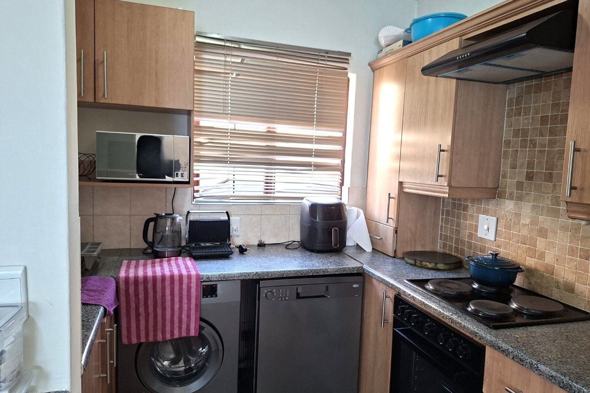A functional kitchen featuring laminate cabinetry, granite countertops, mosaic tile backsplash, and integrated appliances including an oven, hob, and extractor fan.