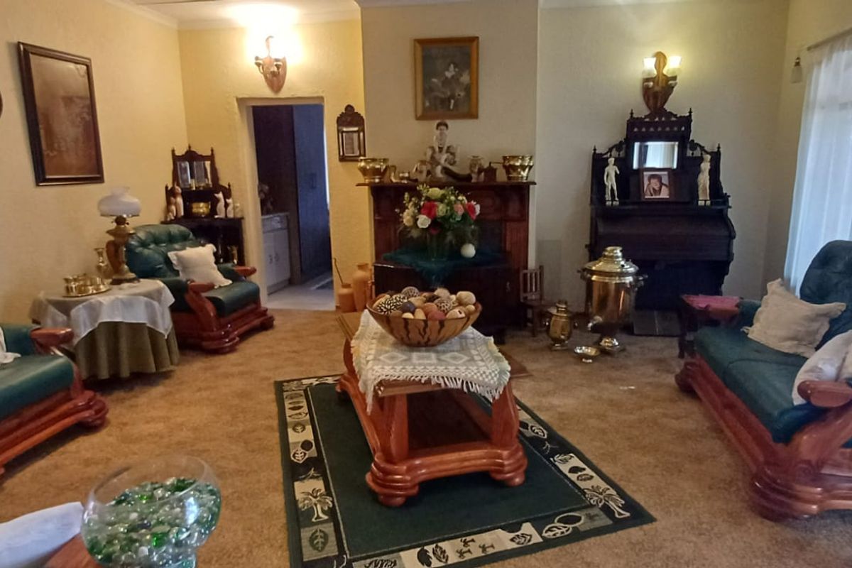 A traditional living room featuring a central fireplace mantel and wall sconce lighting, offering a classic layout with carpeted flooring.
