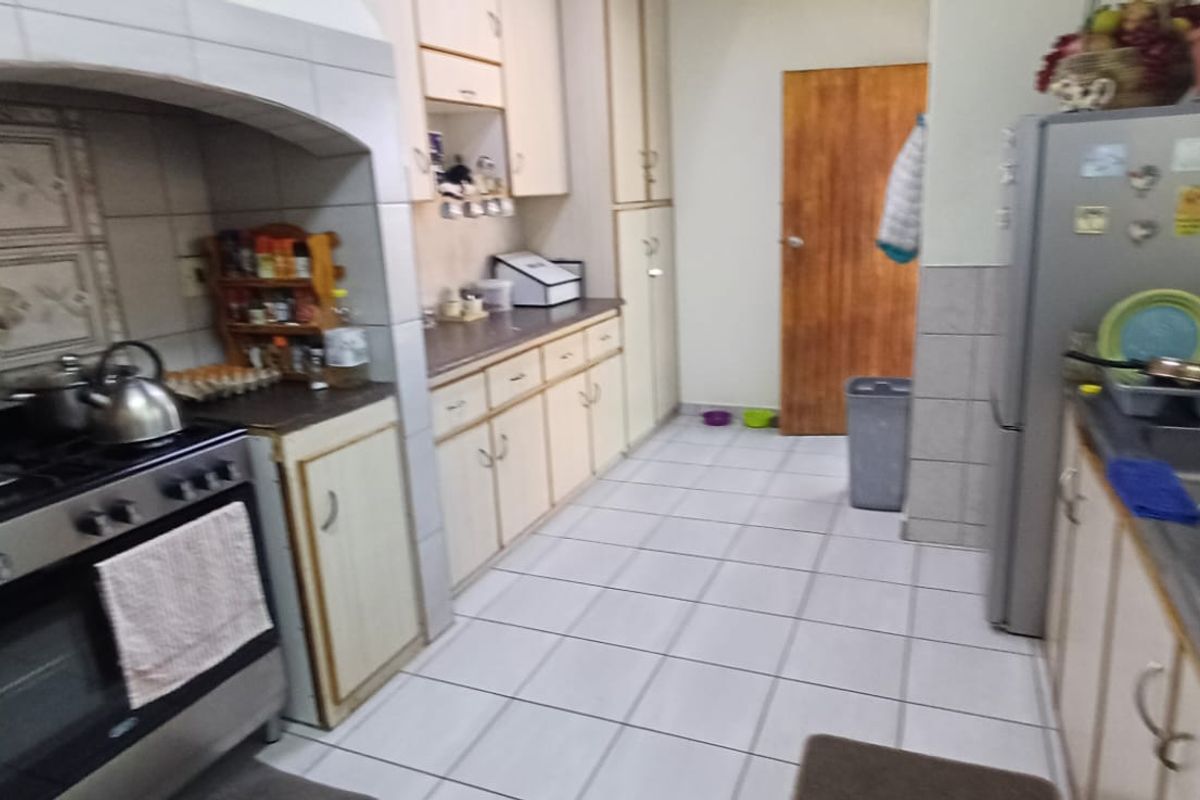 A functional kitchen featuring built-in cabinetry, a gas stove with an extractor hood, and a double basin sink with tiled flooring and splashbacks.