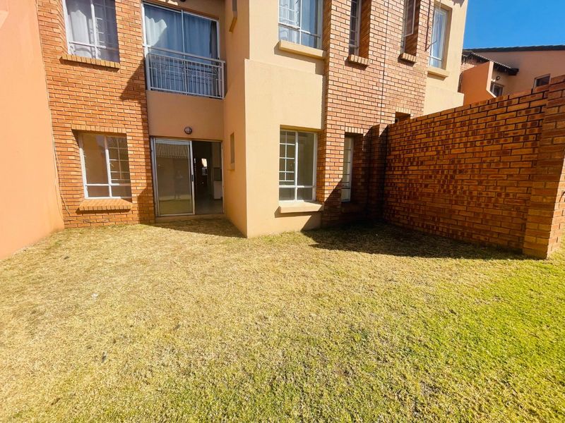 Rear view of the apartment building featuring a face brick facade, sliding glass door access, and a private garden area.