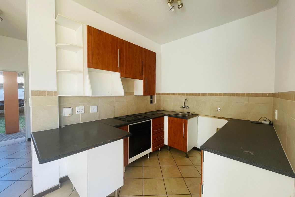 A functional kitchen featuring built-in cabinetry, laminate countertops, and tiled flooring, currently vacant and ready for updates or modernization.