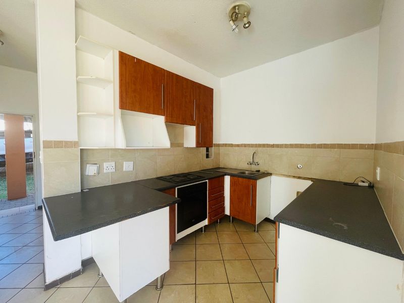 A functional kitchen featuring built-in cabinetry, laminate countertops, and tiled flooring, currently vacant and ready for updates or modernization.