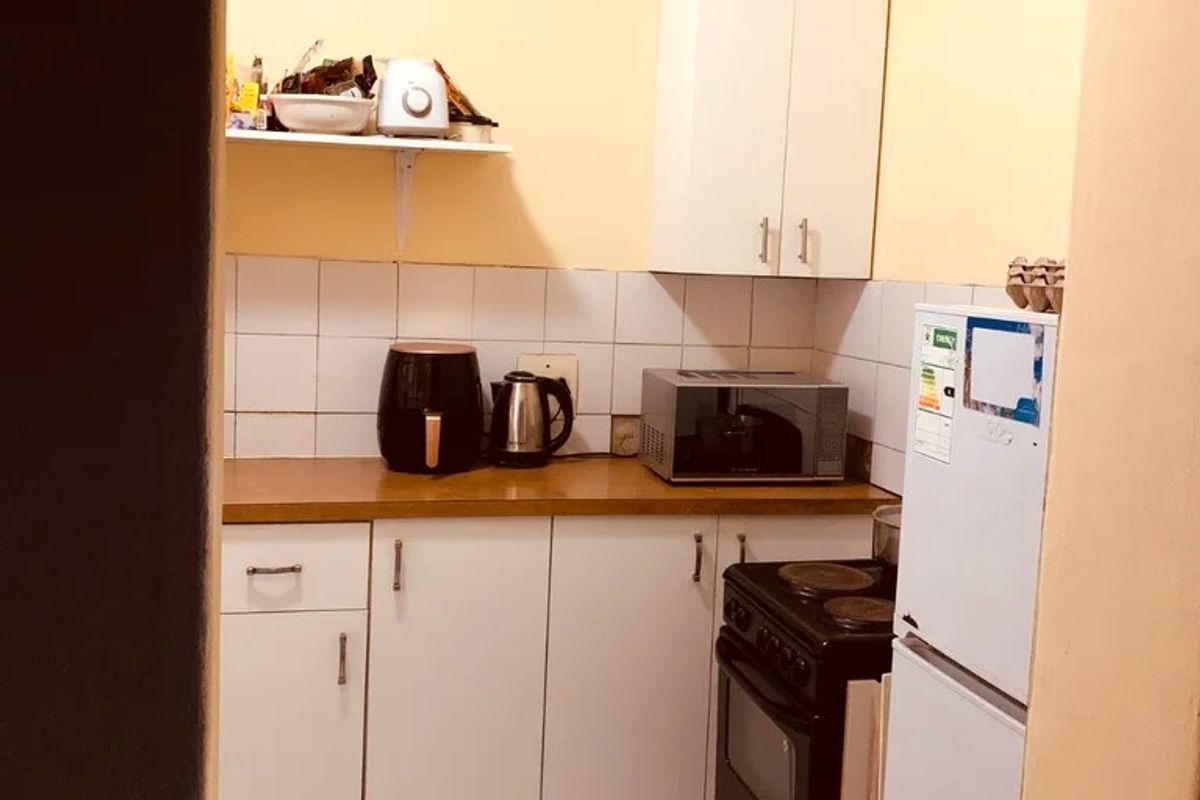 Compact kitchen featuring tiled flooring, a tiled backsplash, laminate countertops, and built-in cabinetry, requiring some cosmetic updates to improve the overall finish.