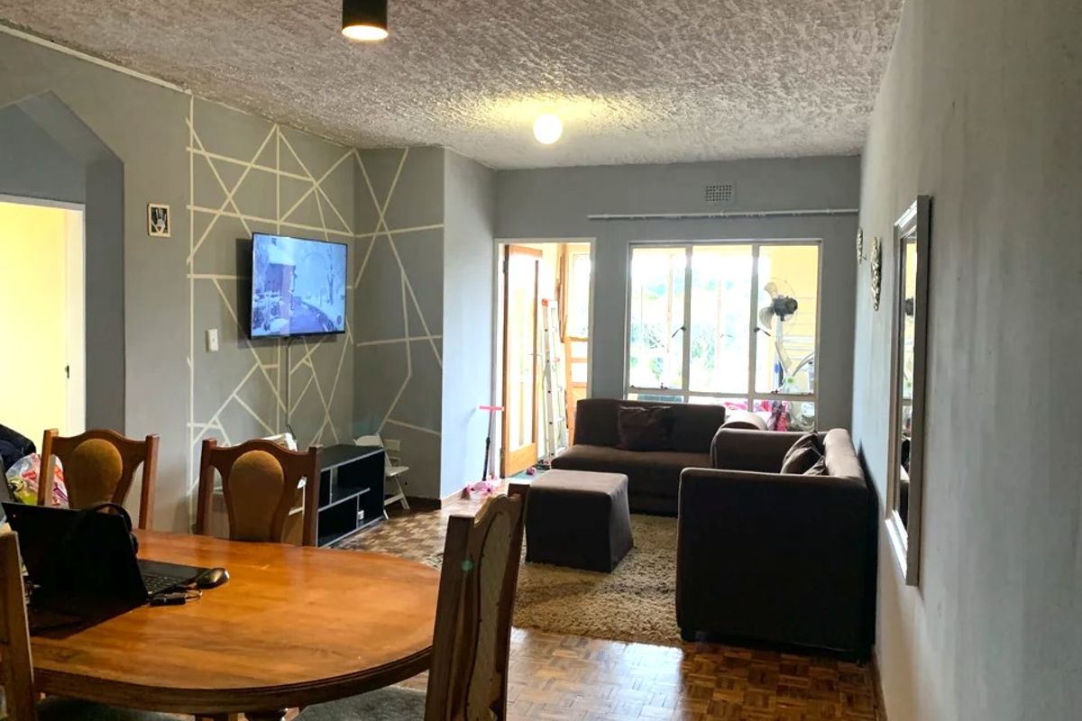 Open plan living and dining area featuring parquet flooring, textured ceilings, and access to an outdoor space through a sliding glass door.