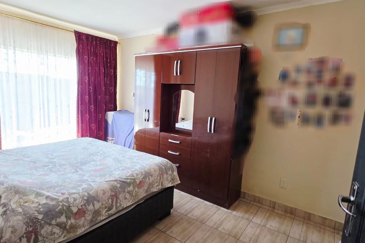 A bedroom featuring tiled flooring and a built-in wardrobe with a central vanity mirror.