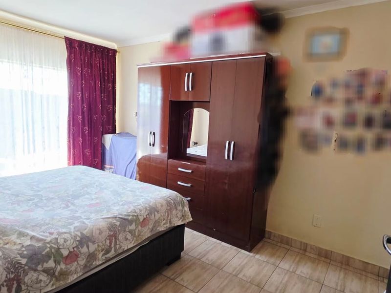 A bedroom featuring tiled flooring and a built-in wardrobe with a central vanity mirror.