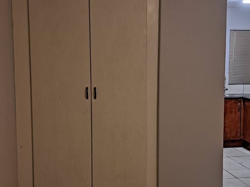 An empty bedroom featuring neutral ceramic floor tiles and a built-in cupboard, offering a blank canvas for potential interior updates.