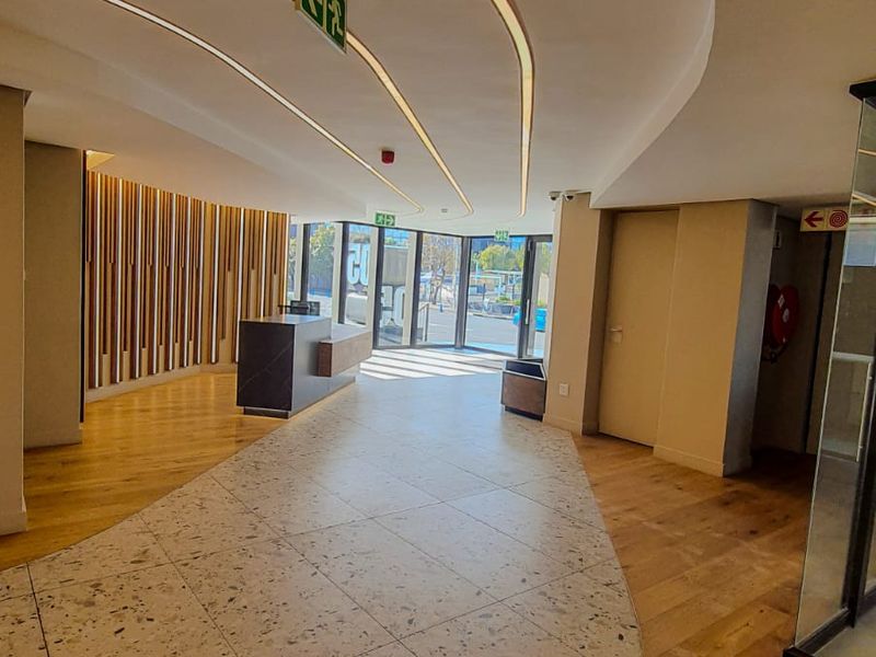 Modern commercial entrance lobby featuring a combination of terrazzo and timber flooring, recessed ceiling lighting, and contemporary timber slat wall paneling.