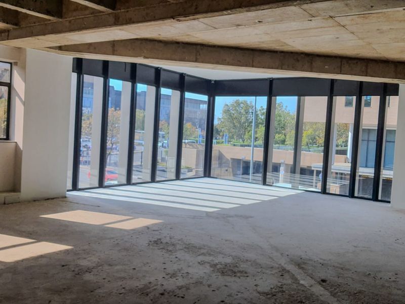 An expansive, open-plan commercial space in shell condition, featuring floor-to-ceiling windows and an exposed concrete ceiling, offering significant potential for custom fit-out.